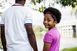 Young girl smiles over her shoulder as she holds her father's hand.