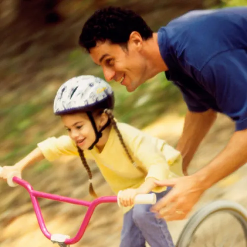 Father teaching daughter how to ride a bike