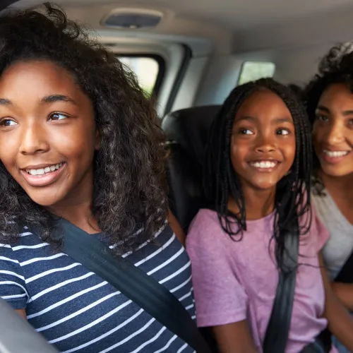 Three sisters look out the car window as they arrive at their parent's home.