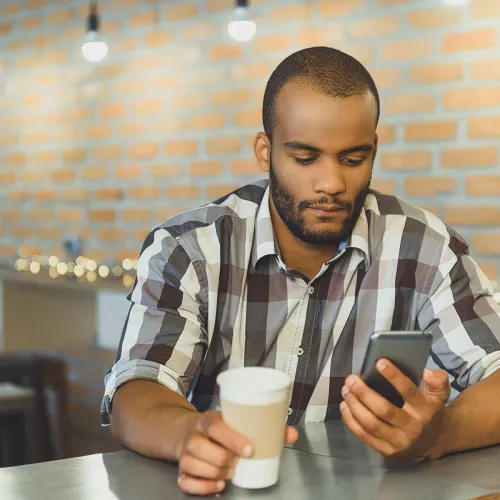 Father stares at a message on his phone while drinking a coffee in a cafe.