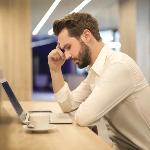 Man looks over his computer with a stressful expression.