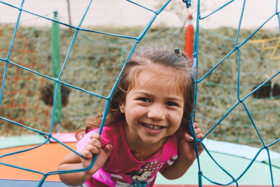 A young girl smiles through a mesh doorway.